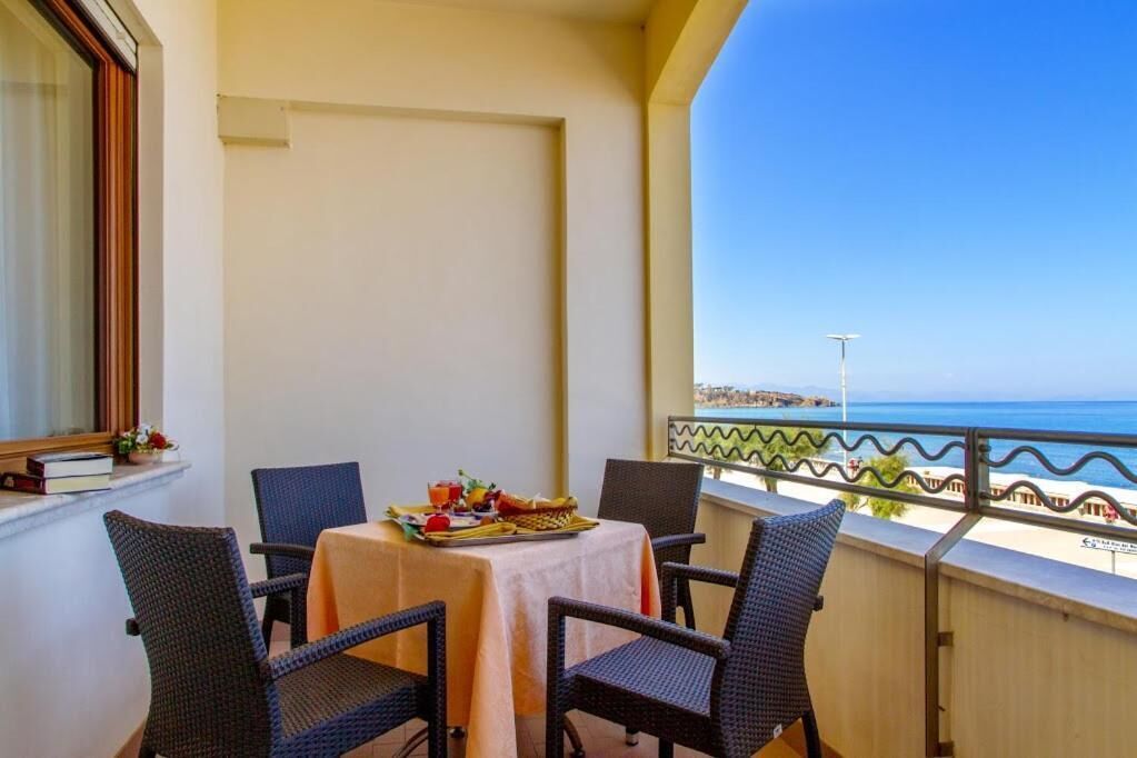 Een balkon met een tafel gedekt voor twee, met uitzicht op een strand.