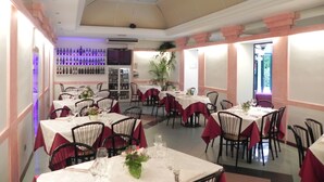 A restaurant with multiple tables set for dining, a bar area with wine bottles, and a ceiling with a grid pattern. - Villa Robinia (Genzano di Roma)