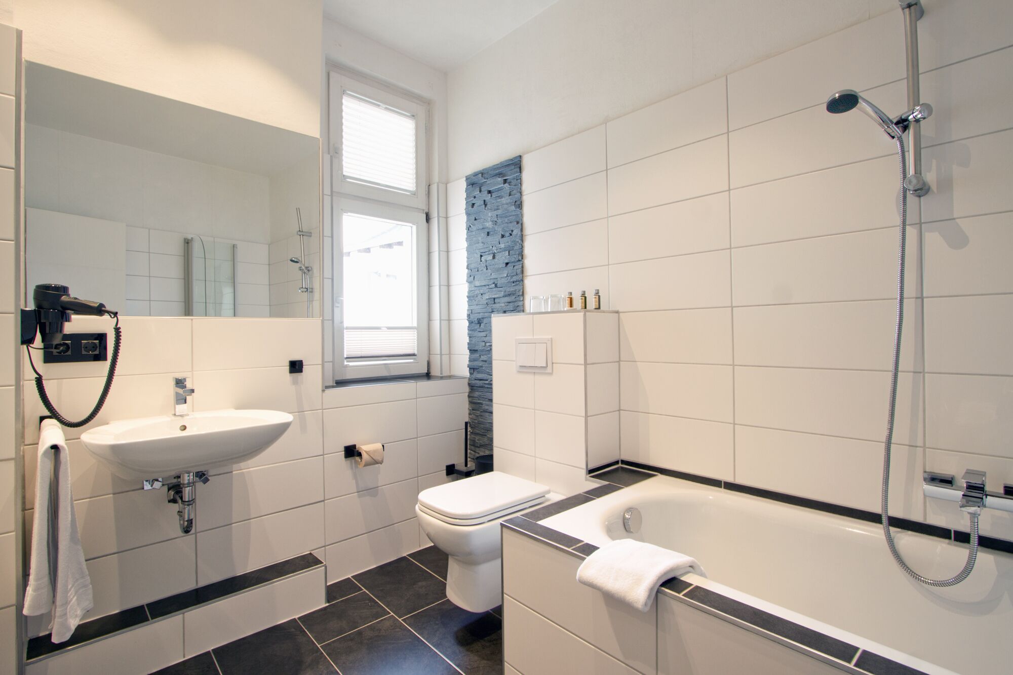 A modern bathroom with a sink, toilet, and bathtub.