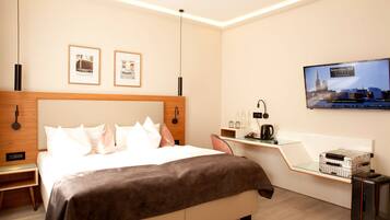 A modern hotel room with a large bed, a desk, a television, and a minibar.