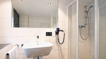 Une salle de bain avec un lavabo blanc, un miroir et une douche.