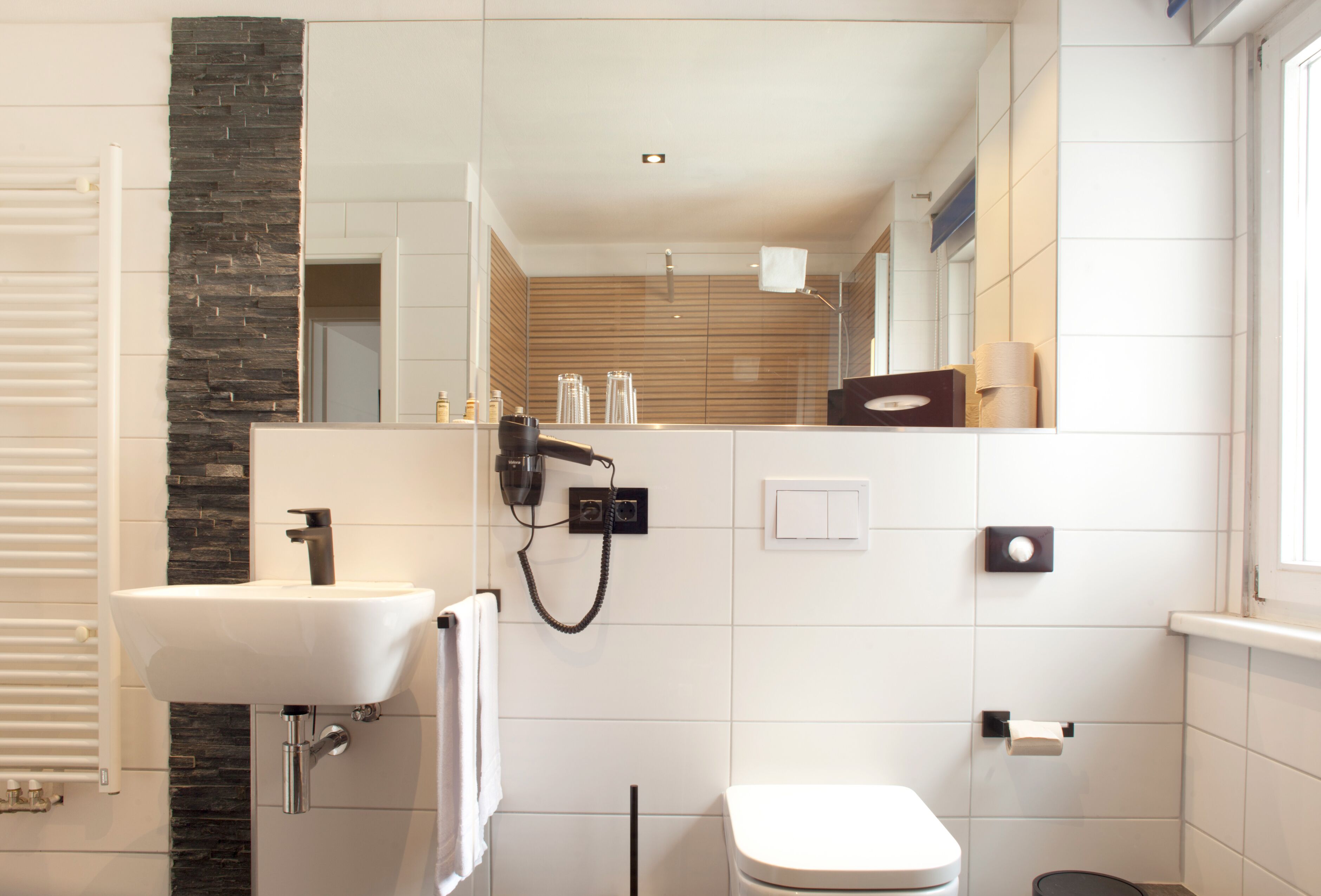 A modern bathroom with a white sink, a toilet, and a shower area.
