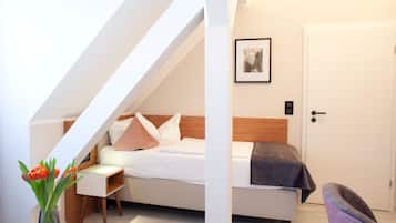 A bedroom with a bed, a nightstand, a chair, a door, and a framed picture on the wall.