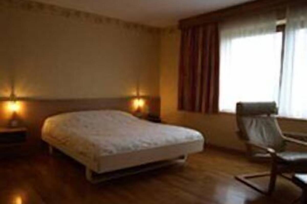 Une chambre d’hôtel avec un lit, une chaise et deux lampes fixées au mur.