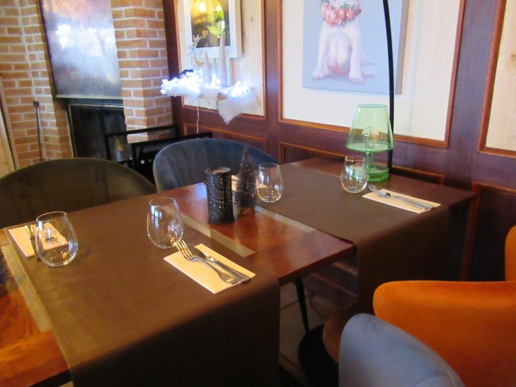A dining table set with cutlery and glasses, a green table lamp, and a framed picture on the wall.