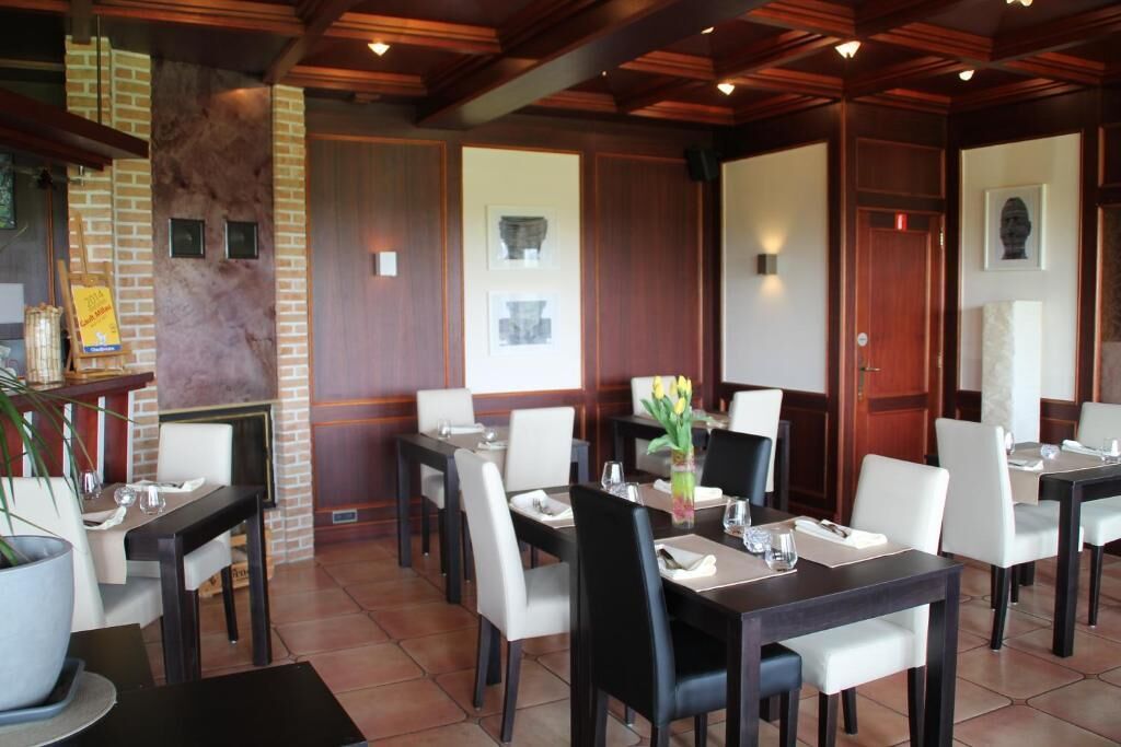 A restaurant with wooden paneling, brick accents, and a fireplace. Tables are set with white chairs and centerpieces.
