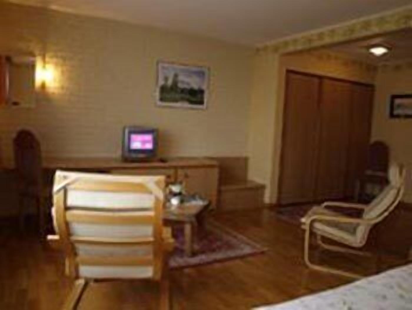 A room with a wooden desk, a television, a chair, and a wardrobe.