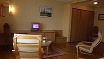 A room with a wooden desk, a television, a chair, and a wardrobe.