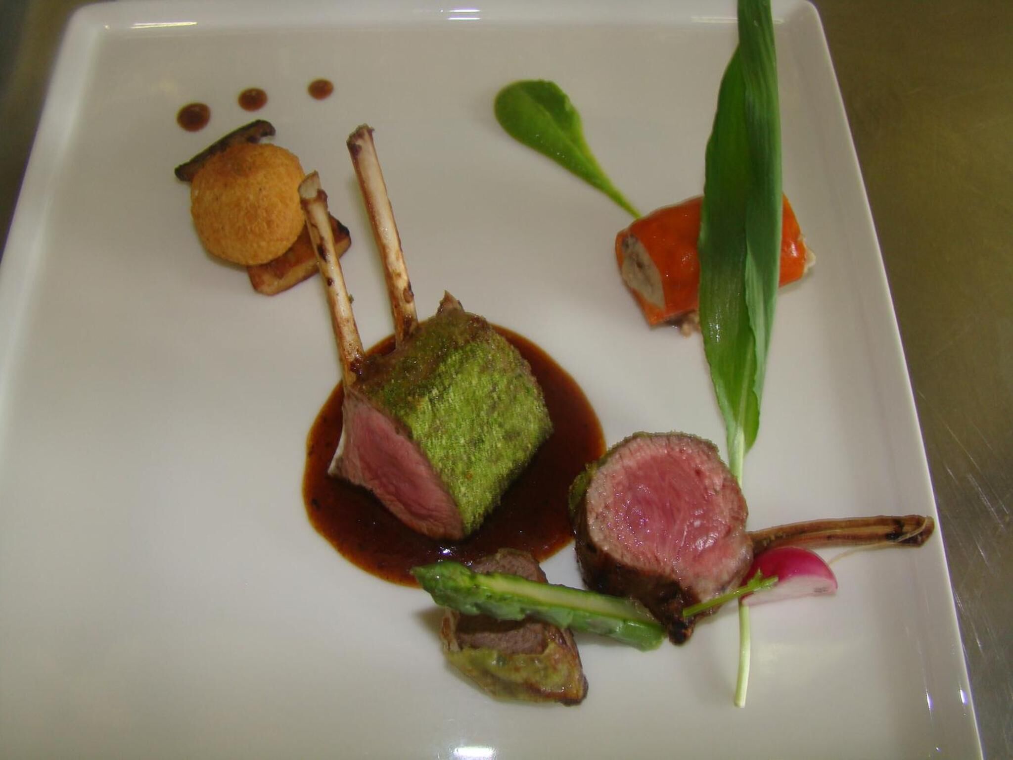 A white plate with a dish of meat, vegetables, and sauce.