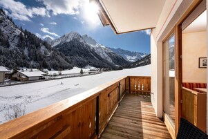 Ein Holzbalkon mit Blick auf schneebedeckte Berge und einen klaren Himmel.