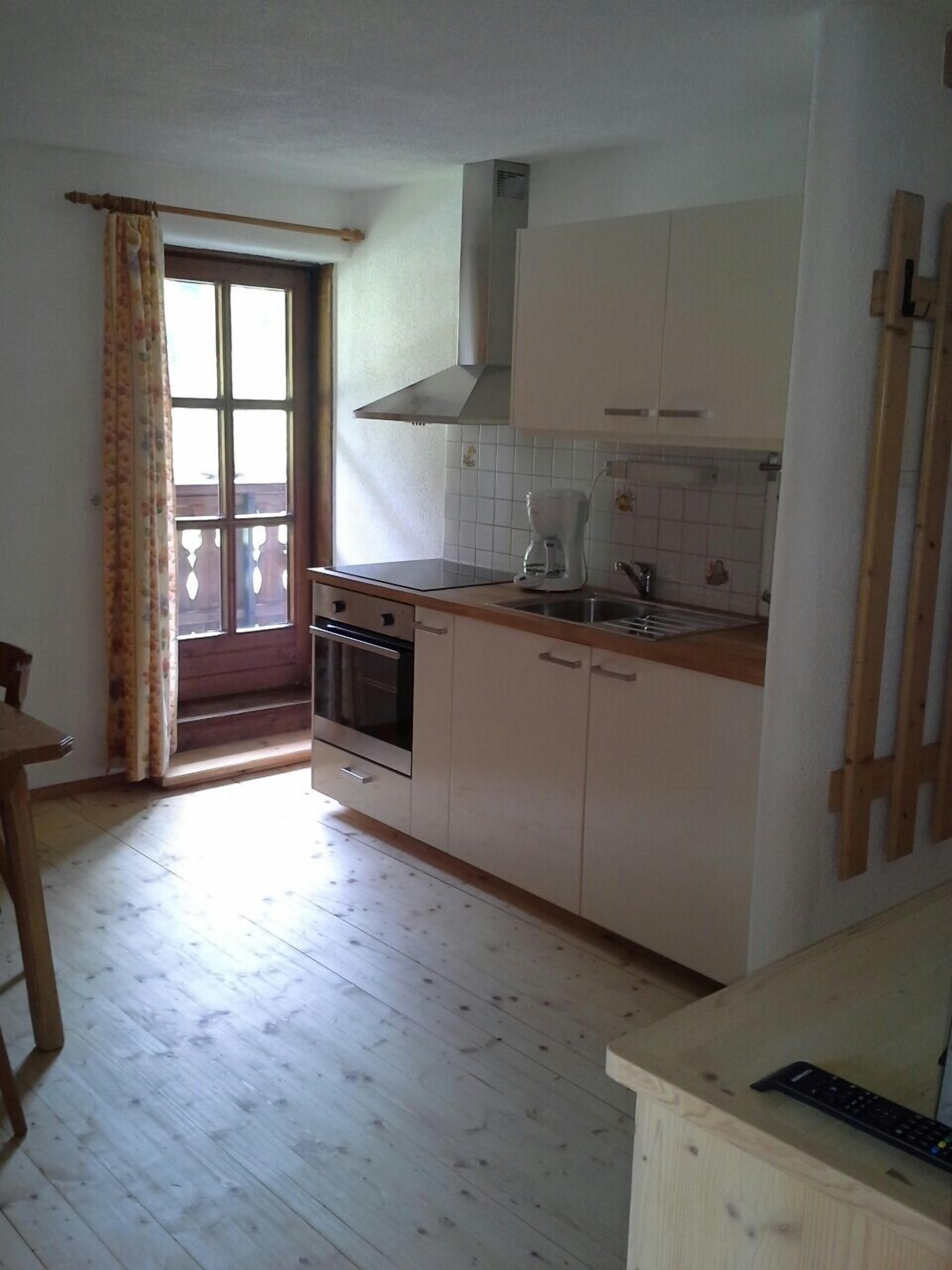 A kitchen with a stove, oven, sink, and a window with curtains.