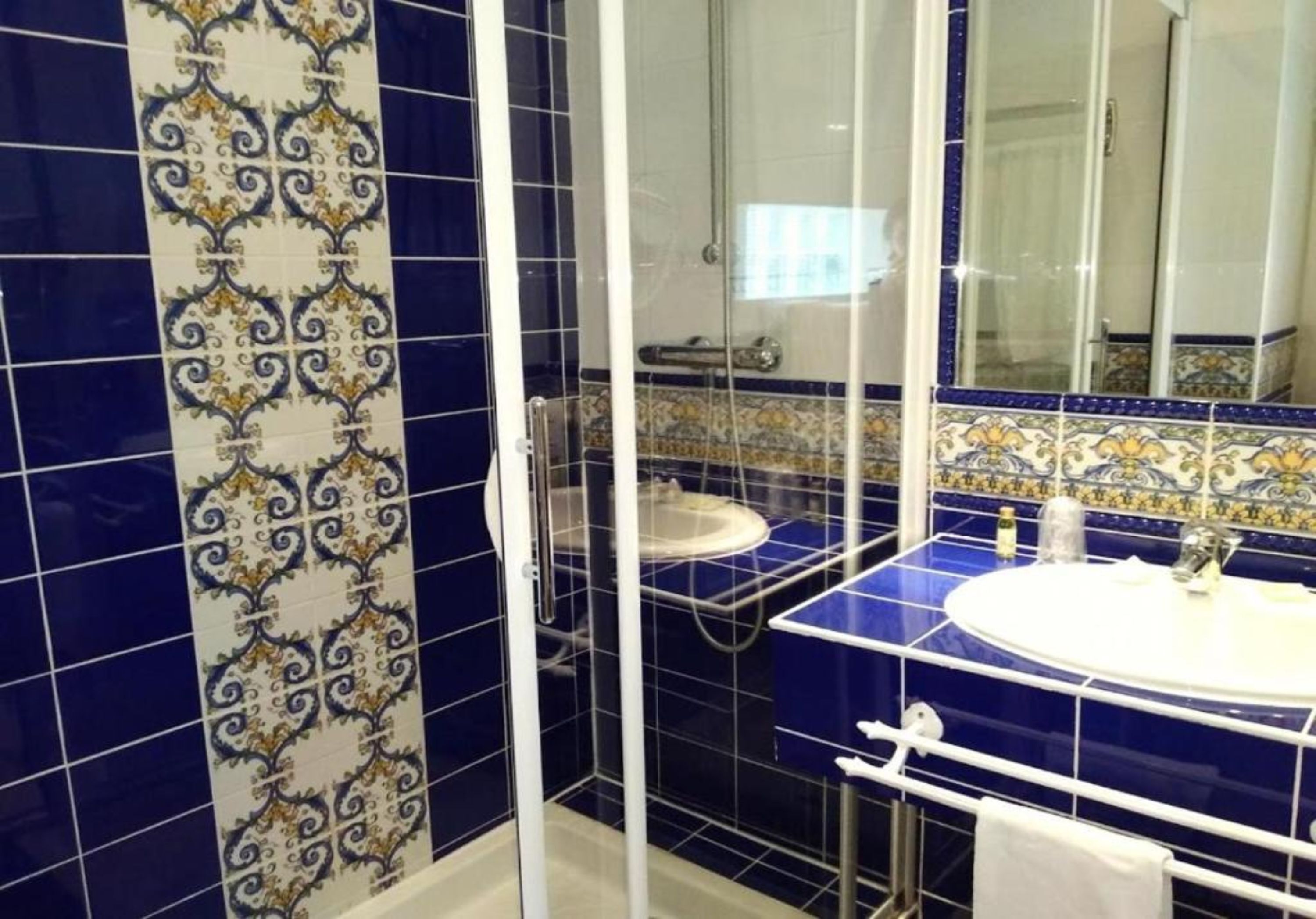 A bathroom with a shower enclosure, a sink, and a mirror.