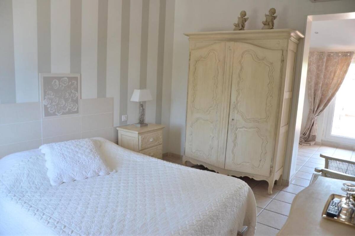 Un dormitorio con una cama grande, un aparador, una mesita de noche y una ventana con cortinas.