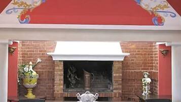 A restaurant with a brick fireplace, white ceiling, and red walls.