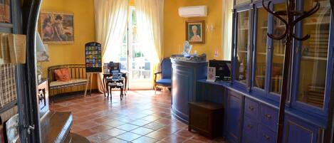 A room with yellow walls, a tiled floor, a blue cabinet with glass doors, a wooden table, and a chair.