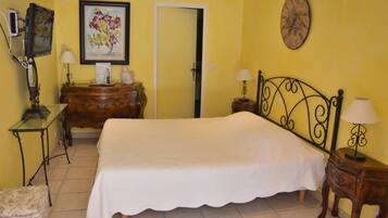 A bedroom with a bed, a dresser, a desk, a chair, a door, and a wall clock.