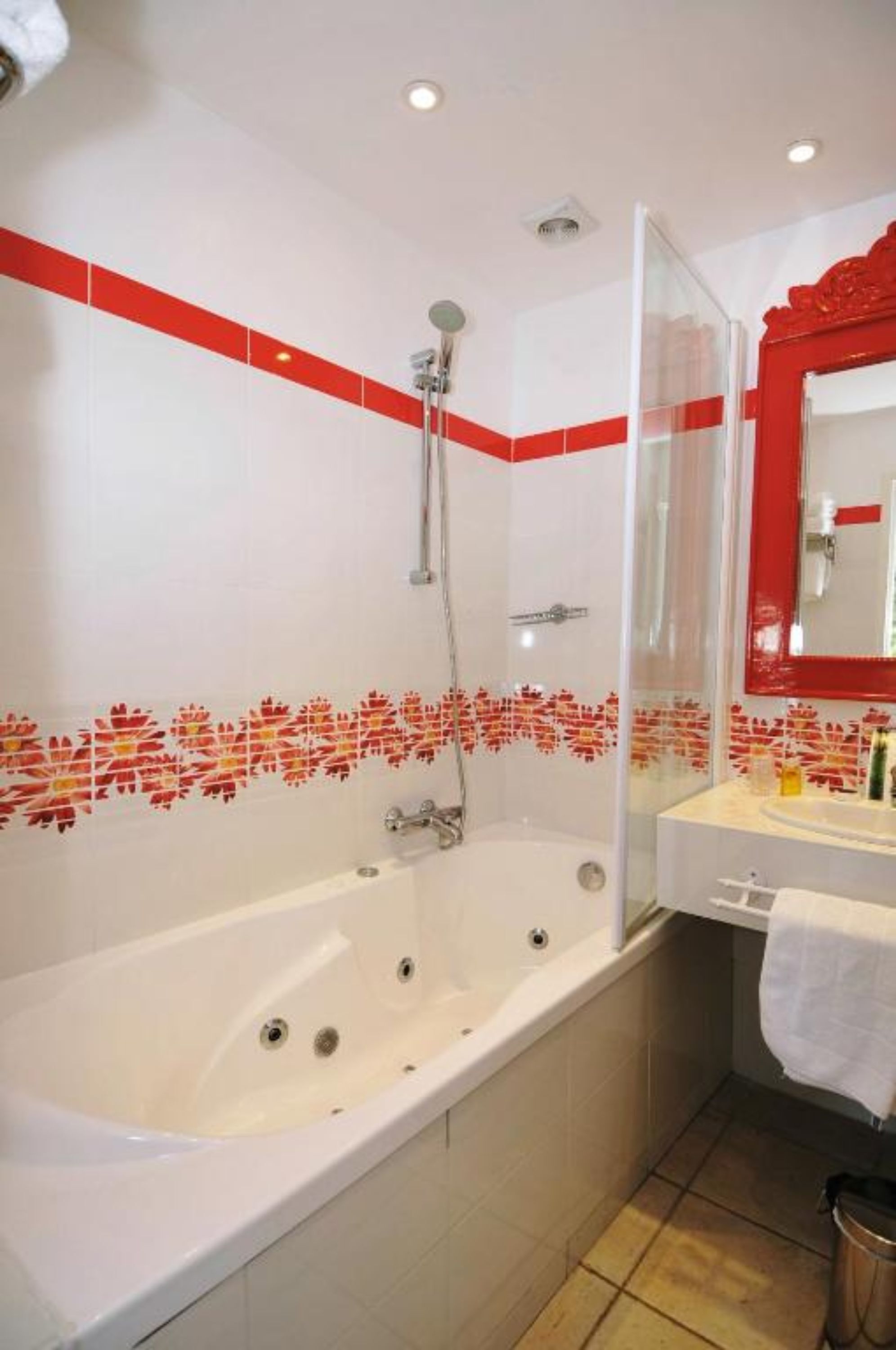 A bathroom with a bathtub, shower, and a mirror with a red frame.