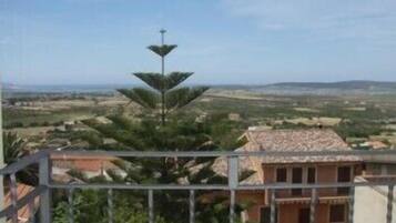 Un balcón con vistas a un paisaje rural, que incluye campos y colinas distantes.