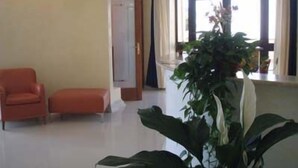 Una sala de estar con un sofá rojo, una mesita y una planta verde grande.