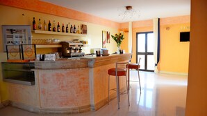 Una cocina con barra, equipada con refrigerador, cafetera y varias botellas.