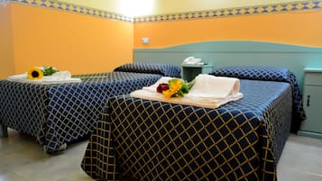 Een hotelkamer met twee bedden, elk met een blauw-en-goud geborduurde spreidek, een nachtkastje met een telefoon en een kleine prullenbak.