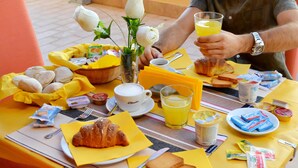 Una mesa con bollos, pan, pasteles, café y jugo para el desayuno.