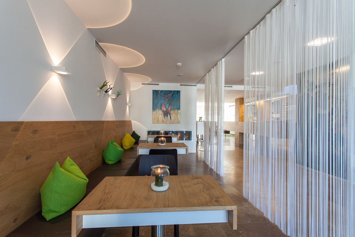 Un intérieur moderne avec des tables en bois, des coussins verts et un tableau accroché au mur.