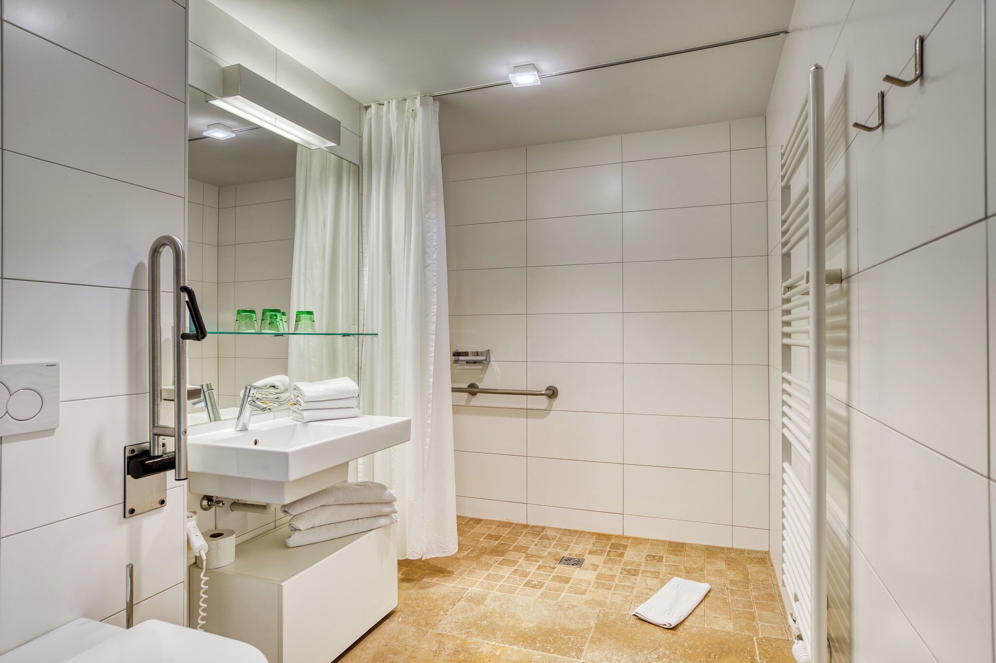 A modern bathroom with a white sink, mirror, and shower area.