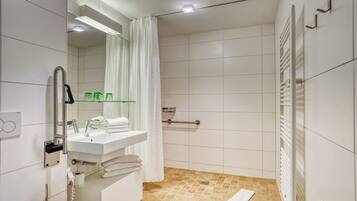 A modern bathroom with a white sink, mirror, and shower area.