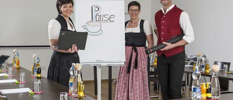 Un salón de reuniones con una pizarra que muestra la palabra 'Pause' y un dibujo de una taza de café.