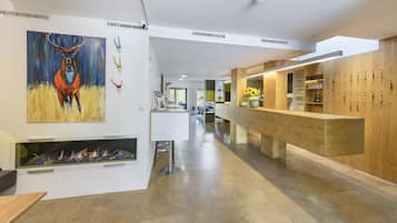Un moderno vestíbulo de hotel con chimenea, mostrador de recepción de madera y una pantalla mural con diversos objetos.