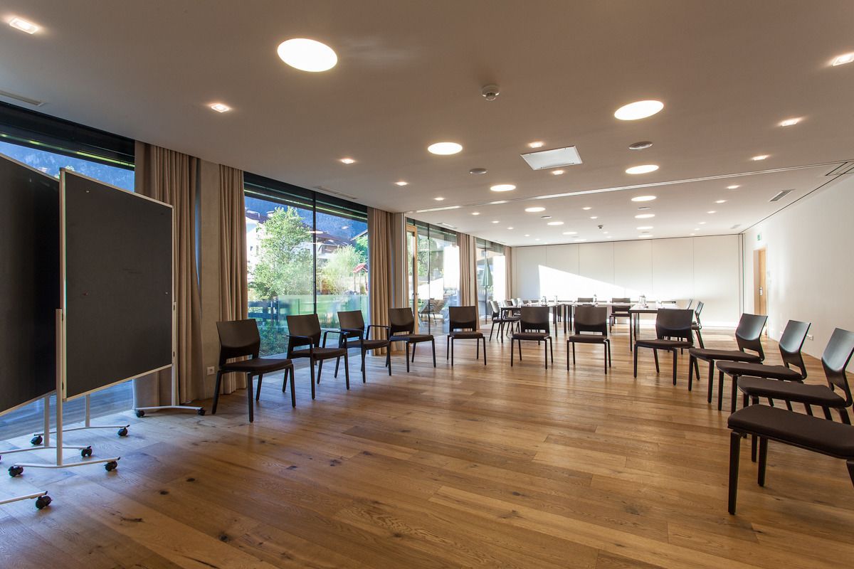 A conference room with a large screen, wooden flooring, and a view of the outdoors.