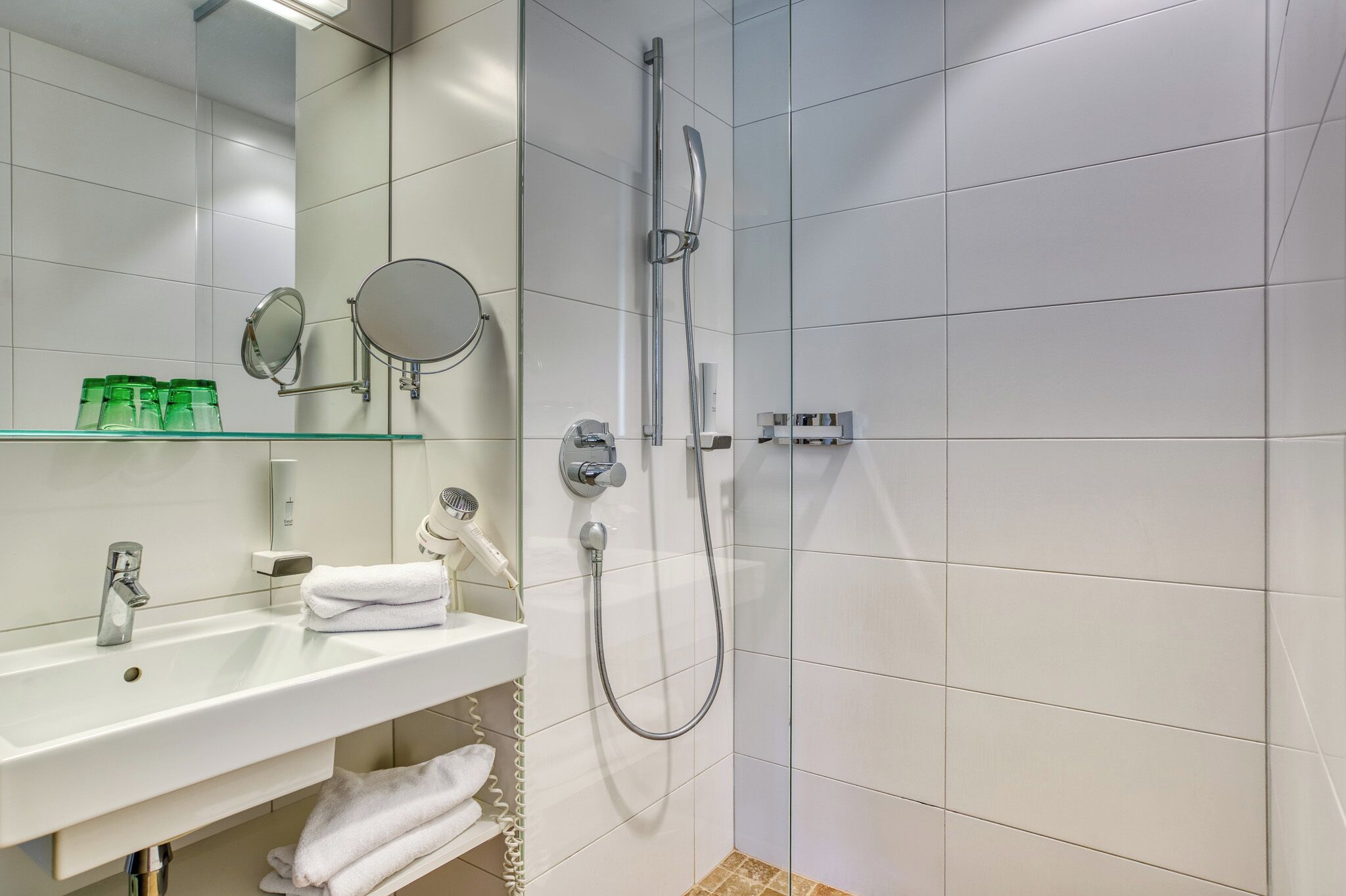 A modern bathroom with a white sink, mirror, and shower.