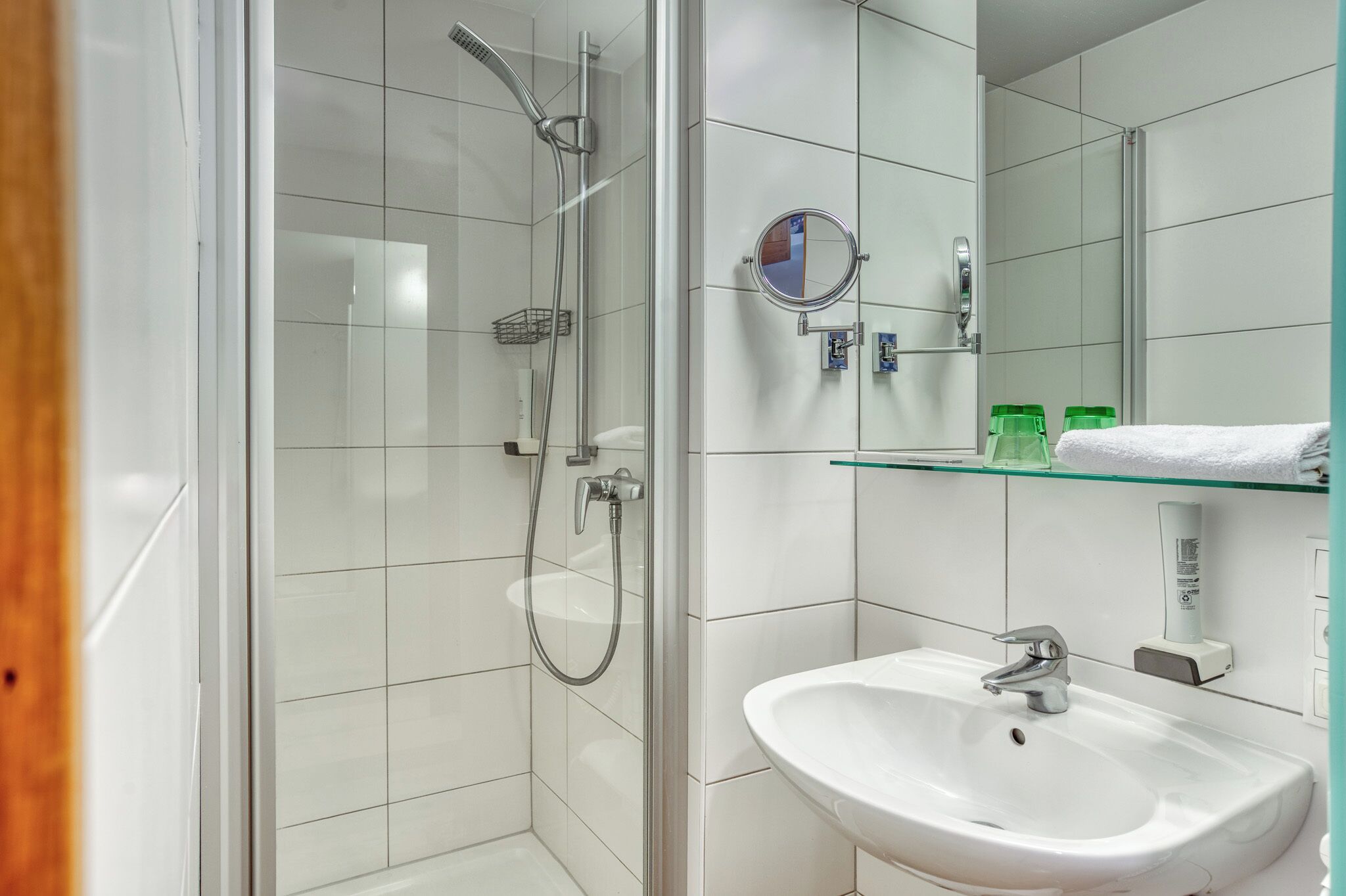 A modern bathroom with a glass shower enclosure, a white sink, and a mirror above it.