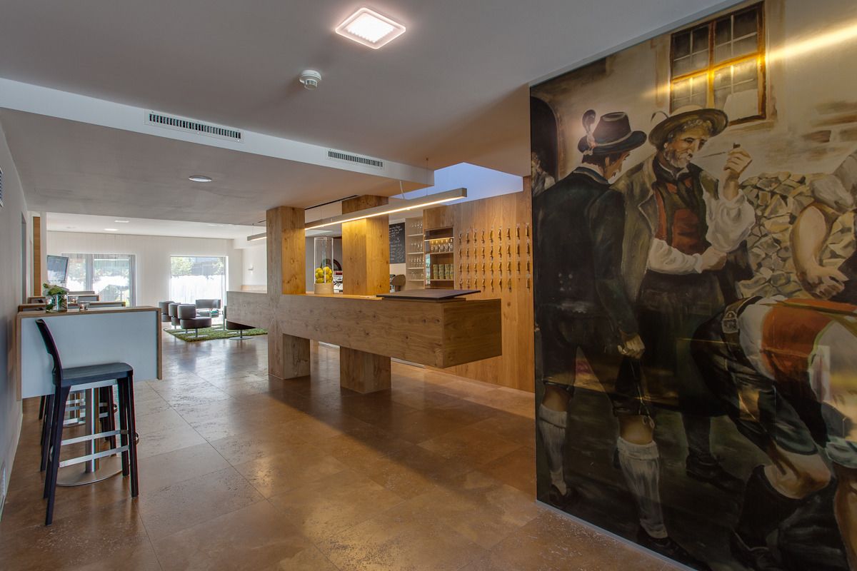 Un interior moderno con una zona de bar, muebles de madera y un mural.