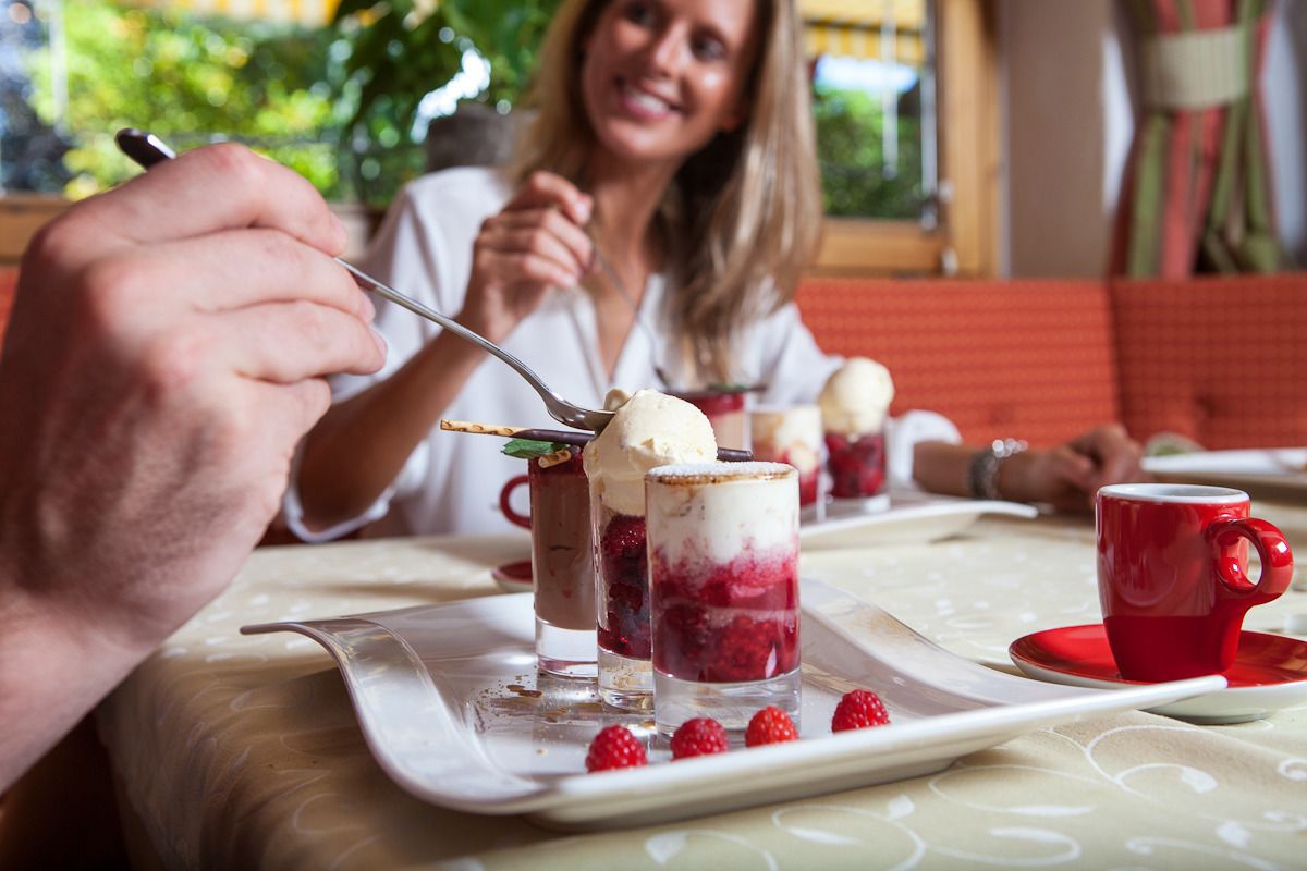 A dining table with dessert cups, a red cup, and a spoon.