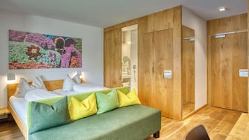 Una habitación de hotel moderna con una cama, un sofá verde, un armario de madera y un cuadro abstracto colorido en la pared.