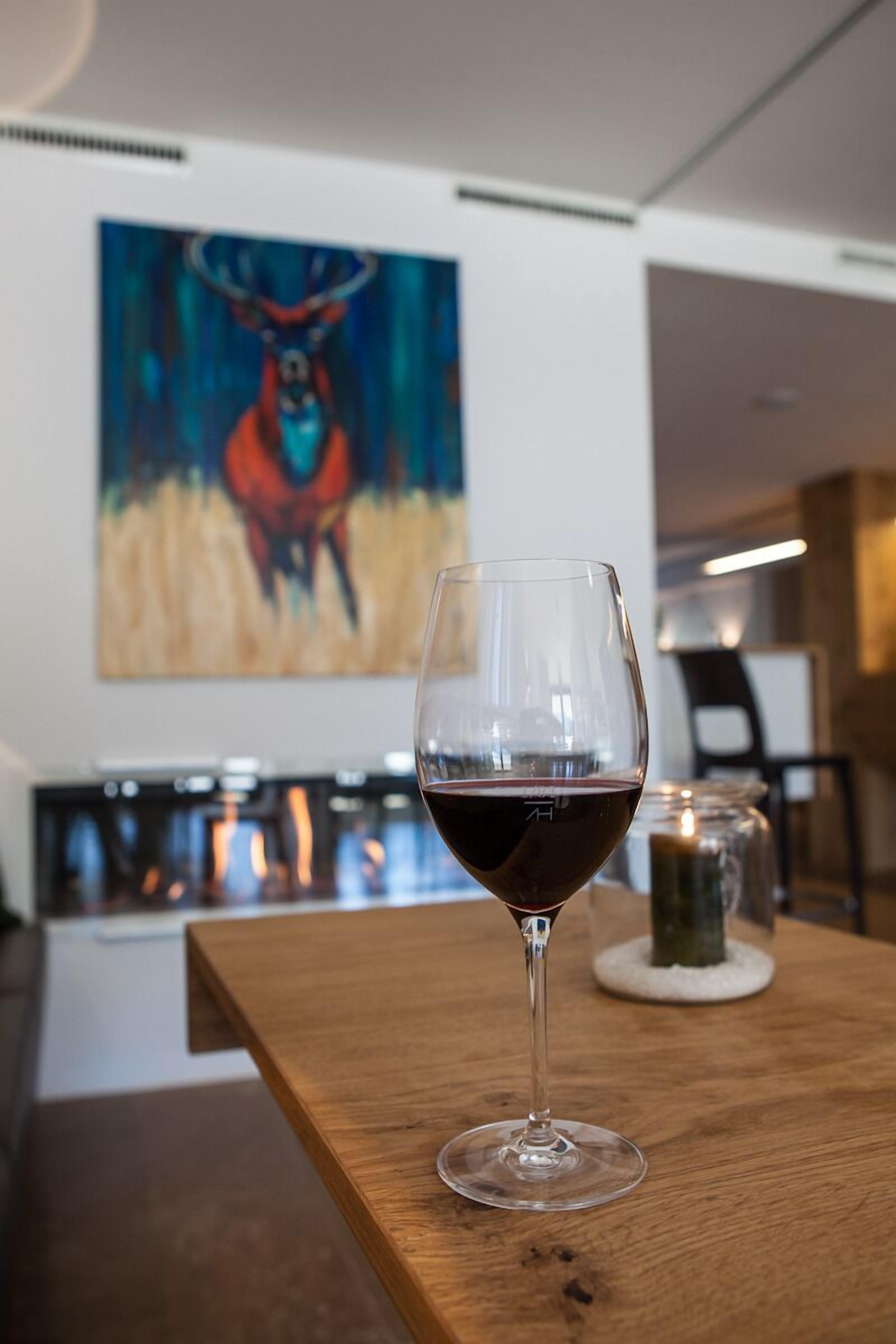 Un bicchiere di vino su un tavolo di legno con un quadro sullo sfondo.