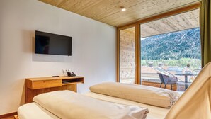 Un dormitorio con televisor, escritorio de madera y vistas a un paisaje montañoso.
