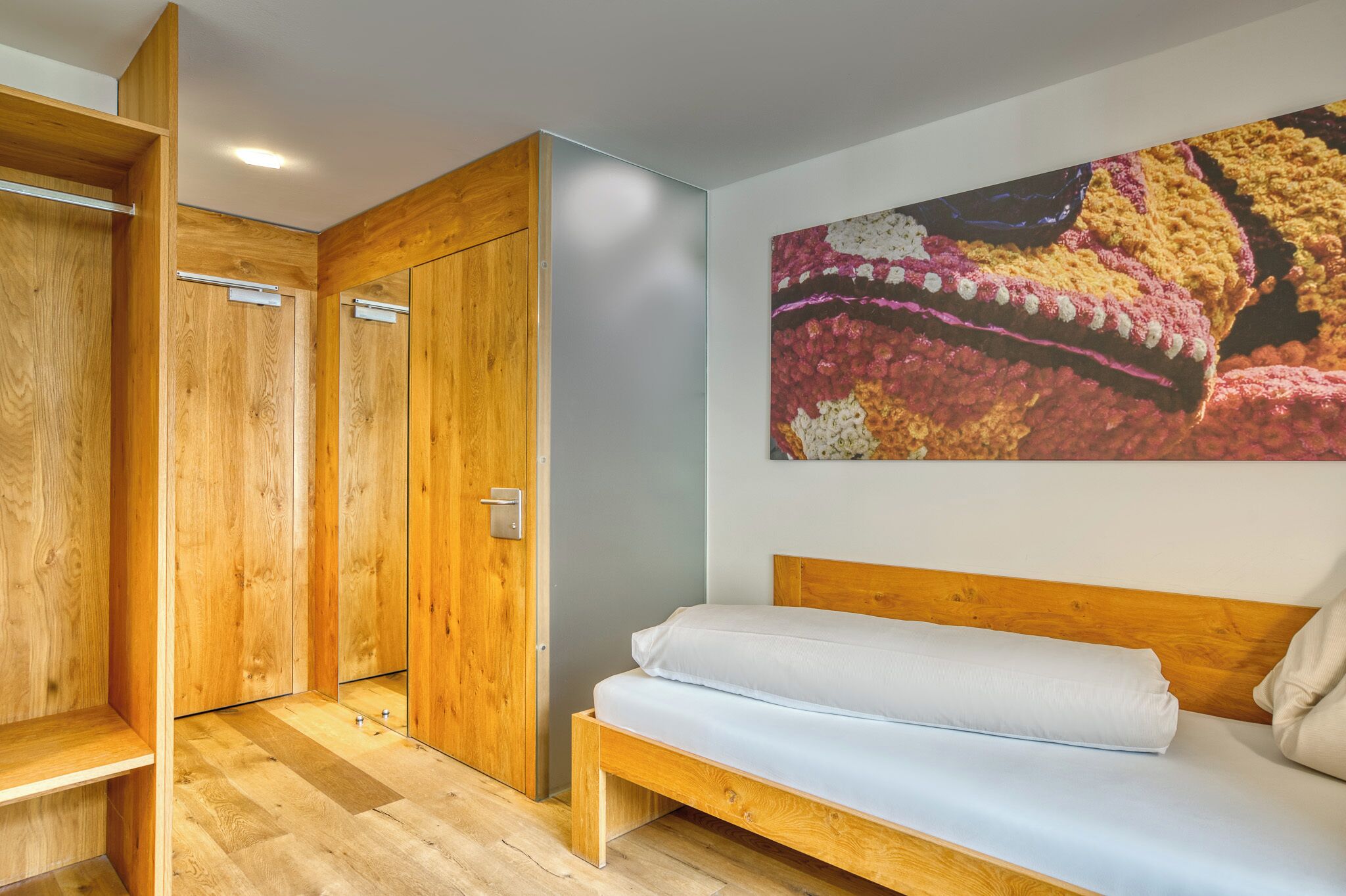 Un dormitorio con una cama de madera, un armario y un cuadro abstracto de colores en la pared.