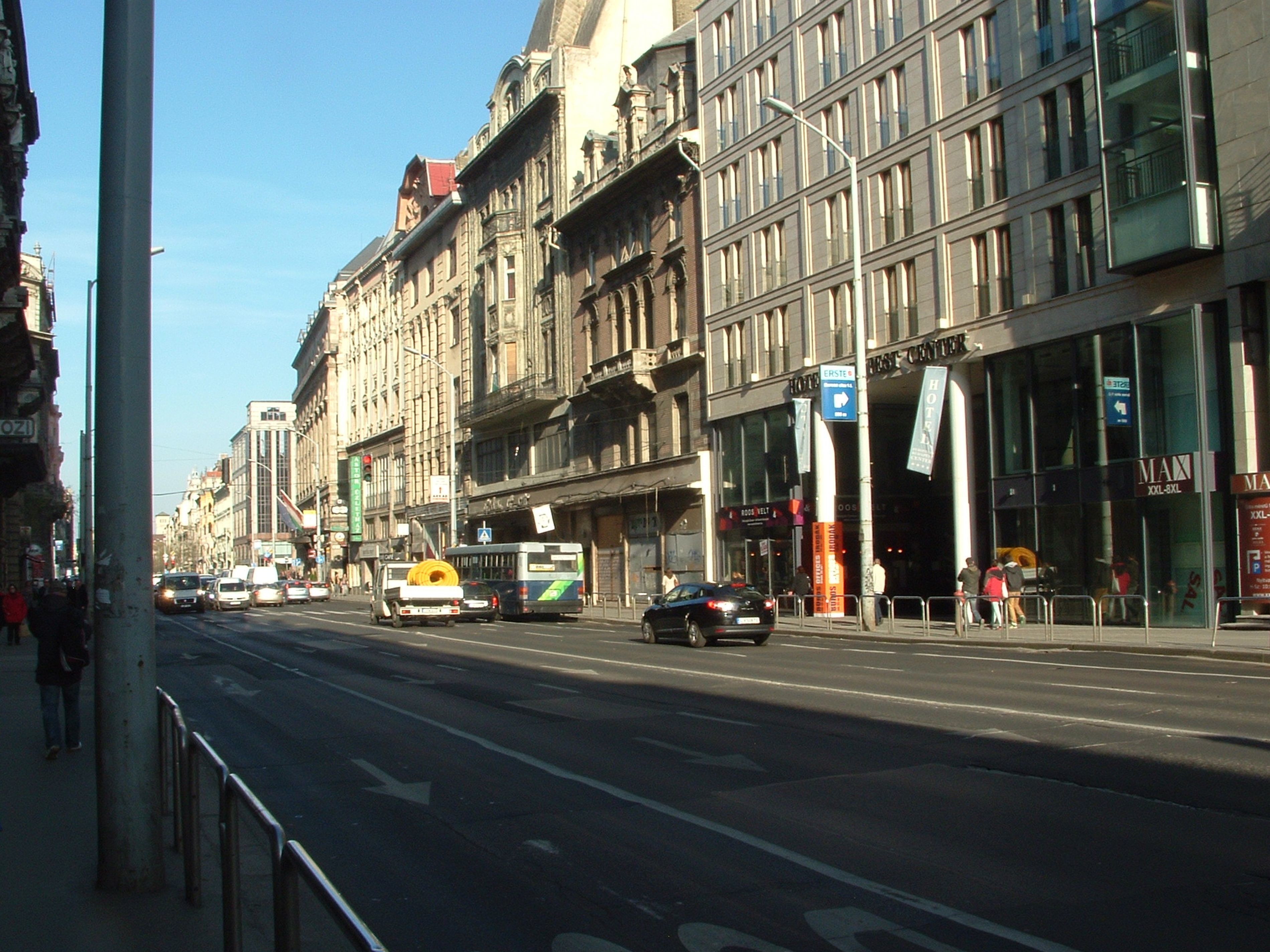 A street view with a building featuring a large glass facade, a sign for 'HOTEL BEST CREATIVE', and a 'MAX' sign indicating room sizes.