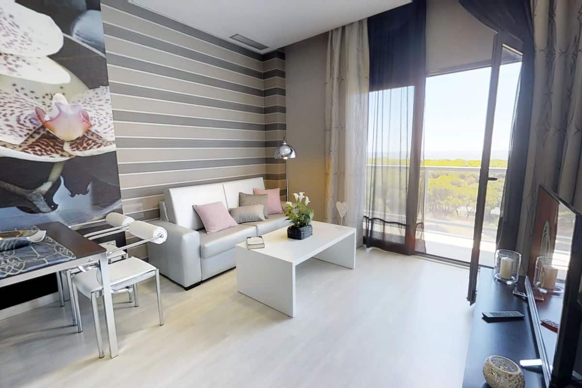 A modern living room with a sofa, coffee table, and a dining area.