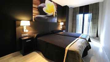 Una habitación de hotel moderna con una cama grande, dos lámparas de noche, una mesita de noche y una obra de arte floral de gran tamaño en la pared.