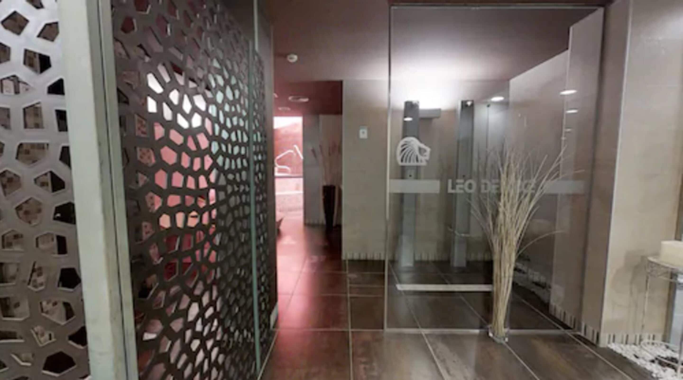 A hallway with a decorative metal partition, a glass door, and a tiled floor.
