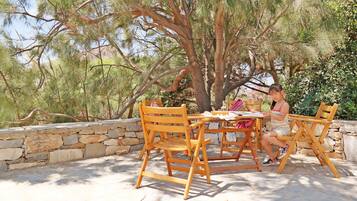 Sit and unwind in this serene outdoor seating area surrounded by lush greenery and a natural stone wall.
