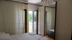 A hotel room with a large bed, a mirror, and a view of the outdoors. - Apartments and rooms Rogosic (Hvar)