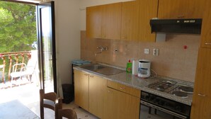 A kitchen with wooden cabinets, a granite countertop, a gas stove, and a coffee maker. - Apartments and rooms Rogosic (Hvar)
