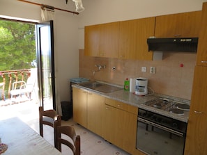 A kitchen with wooden cabinets, a granite countertop, a gas stove, and a coffee maker.