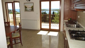 A kitchen with a view of the sea, a dining area with chairs, and a table. - Apartments and rooms Rogosic (Hvar)