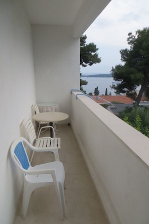 A balcony with a table and chairs, overlooking a body of water and buildings. - Apartments and rooms Rogosic (Hvar)